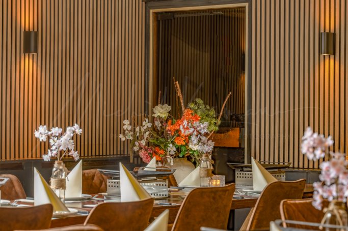 Restaurantinterieur met gedekte tafels, bloemen en warme houten wanden